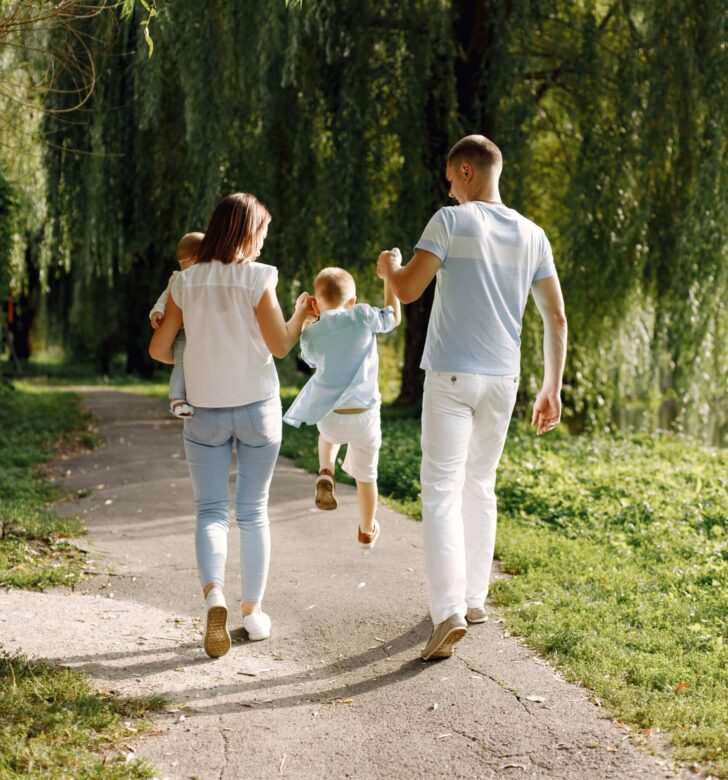 back view photo of a family walking in a park on summer