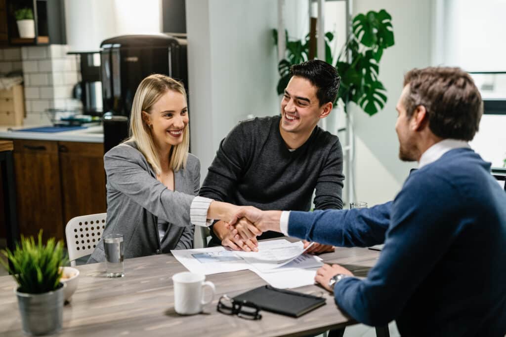 young happy couple handshaking with financial advisor at their home.