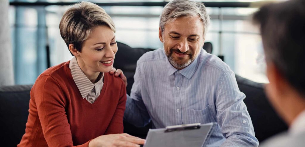 happy couple going through terms of an agreement during a meeting with financial advisor.