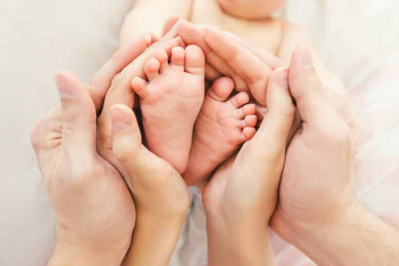 mom and dad hold baby legs.