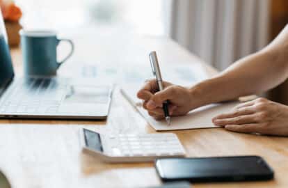 business women write on notepad with pen to calculate financial