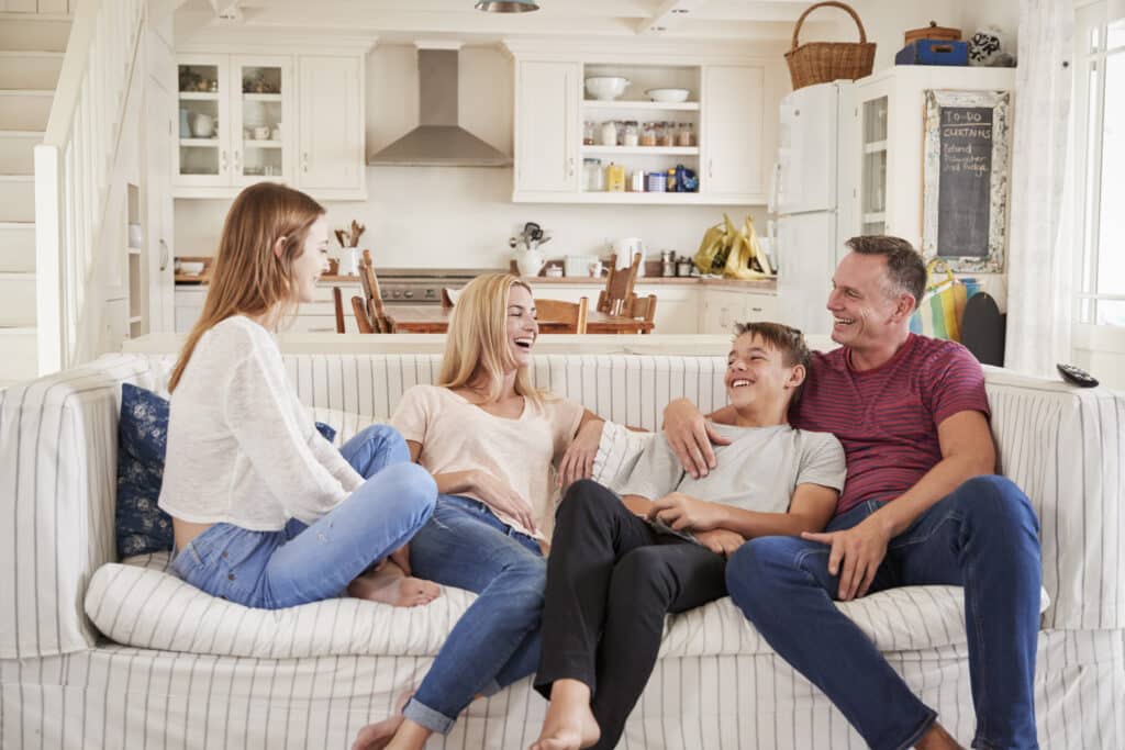 family with teenage children relaxing on sofa together