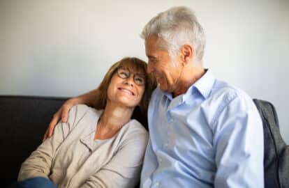 smiling older man and woman sitting on sofa together